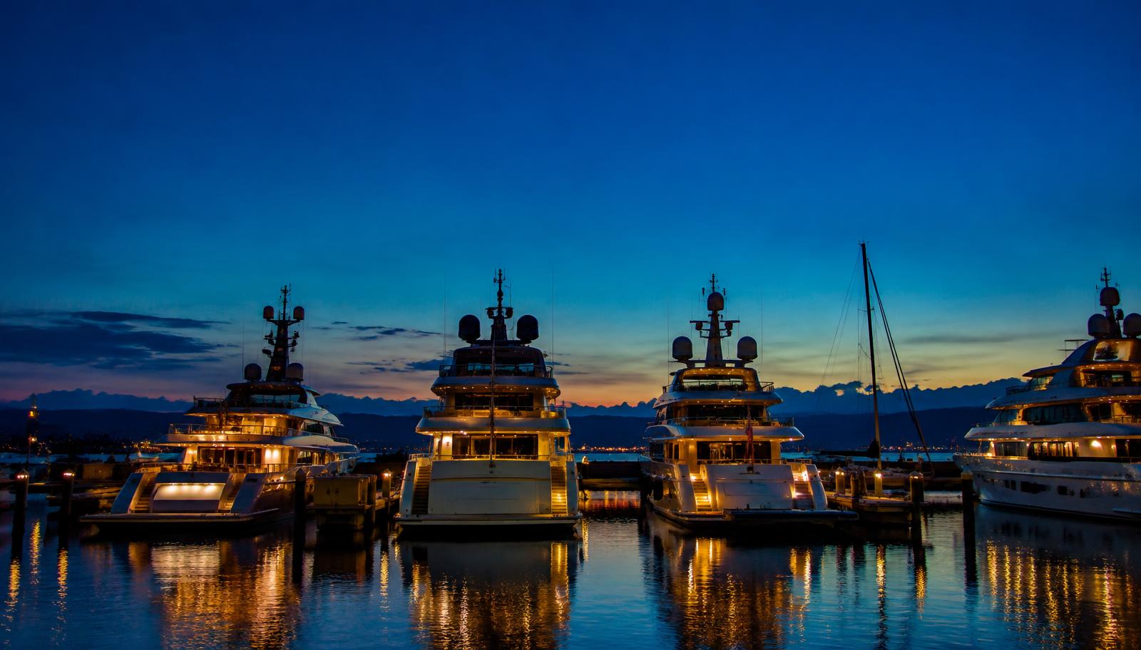 Design visual of superyachts moored in a marina at twilight